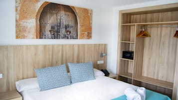 Una camera d'albergo con un letto, un armadio in legno, un appendiabiti e un'opera d'arte a parete.