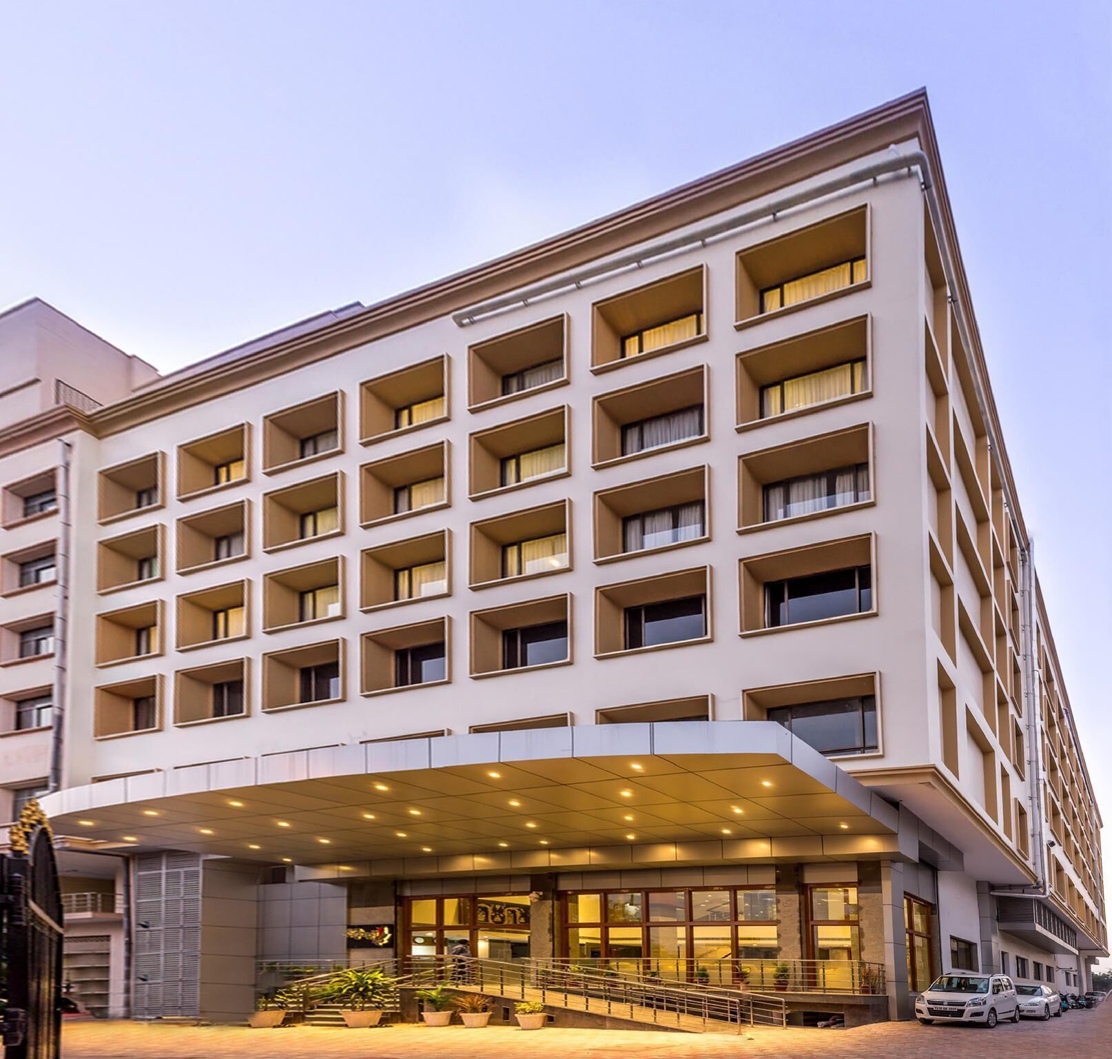 A multi-story hotel with a modern facade, large windows, and a covered entrance area.