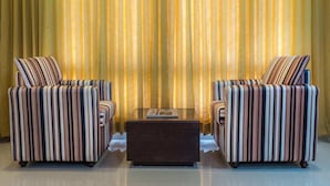 A room with two striped armchairs and a glass coffee table. - OYO Premium Secunderabad Station (Hyderabad)