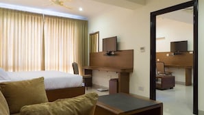 A hotel room with a bed, a sofa, a desk with a chair, a television, and a mirror. - OYO Premium Secunderabad Station (Hyderabad)
