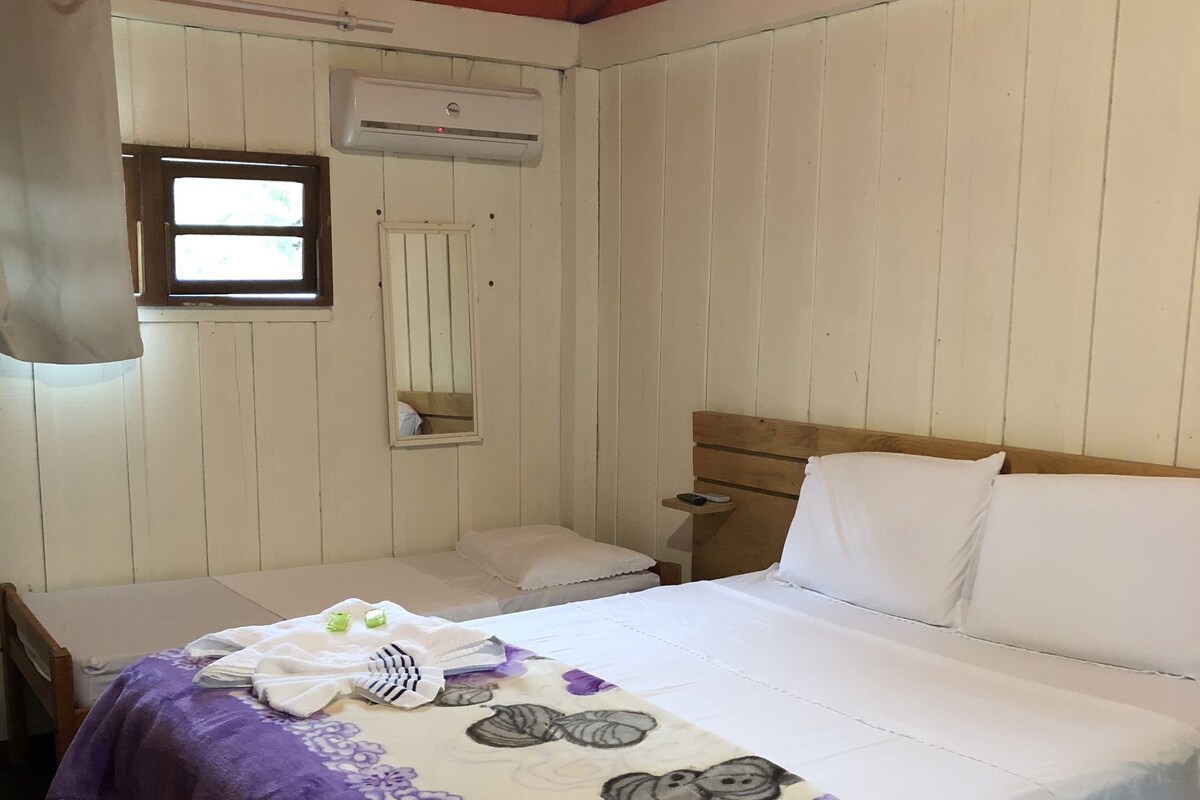 A room with a bed, a nightstand, a window, and a wall-mounted air conditioner.