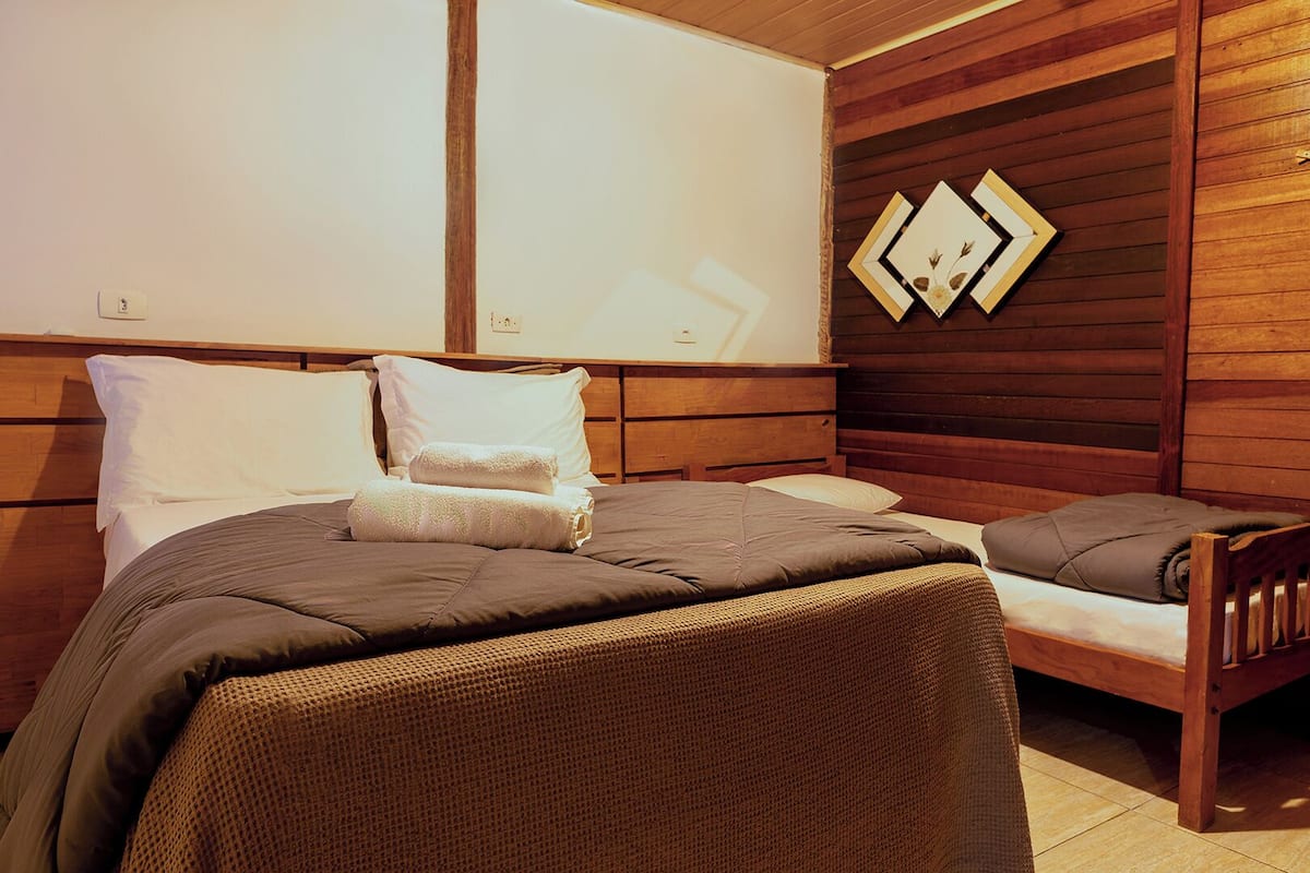 Quarto bem organizado com uma cama, um pequeno sofá e uma cabeceira de madeira.