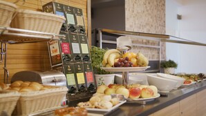 A buffet with various food items including fruits, pastries, and a coffee machine. - Hotel Bildungsblick (Kirchseeon)