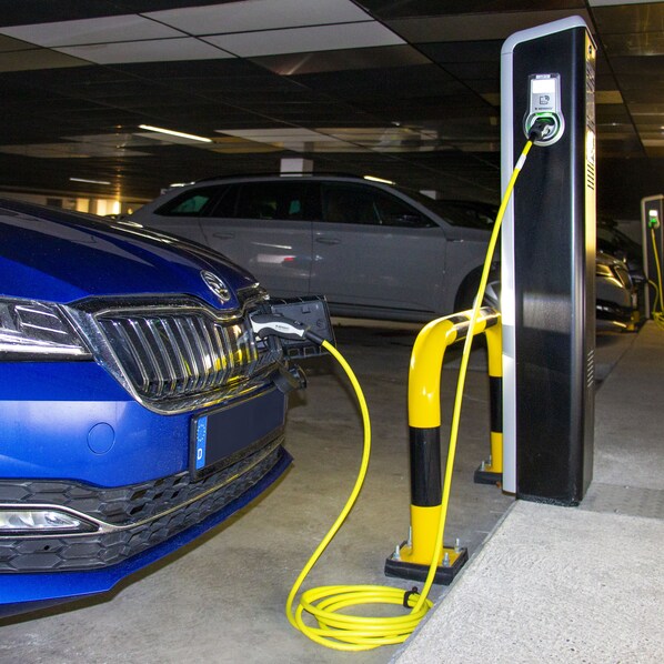 Un coche azul estacionado en una estación de carga dentro de un estacionamiento.