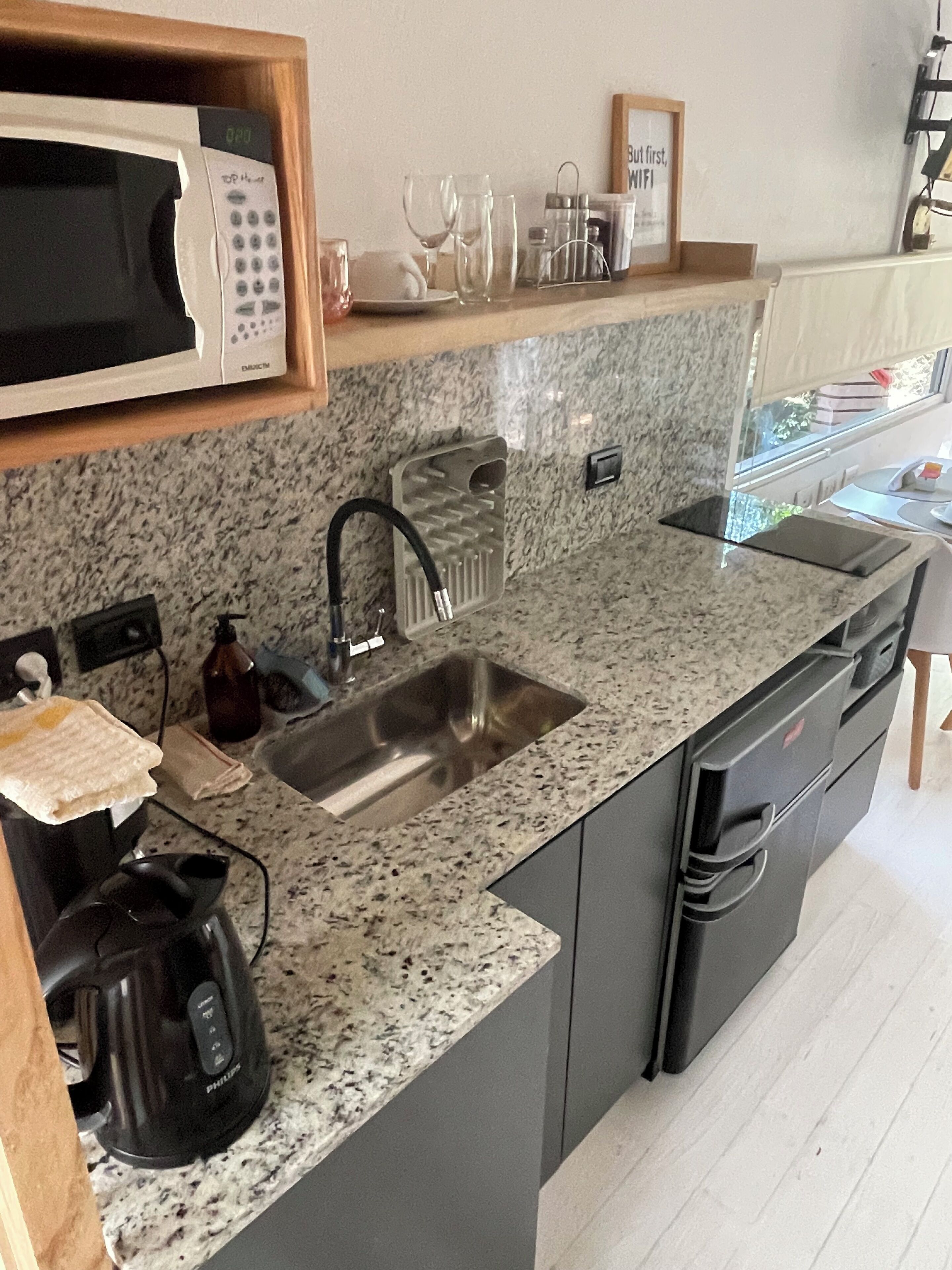 Cucina con piani di lavoro in granito, lavello in acciaio inossidabile, forno a microonde e macchina del caffè.