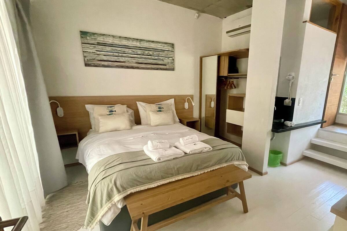 A bedroom with a bed, bedside tables, a bench, a wardrobe, and a window.