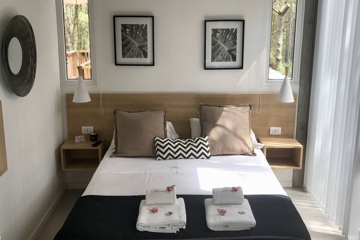 A hotel room with a bed, two nightstands, a mirror, and two framed pictures on the wall.