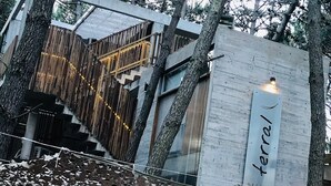 Un edificio moderno con un letrero que dice "terral DESIGN SUITES" y una escalera de madera que conduce a un nivel superior.