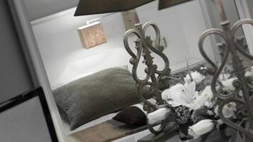 A mirror reflecting a room with a bed, a lamp, and a decorative item.