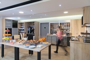 Una cocina moderna con una mesa para buffet, armarios empotrados y una cafetera.