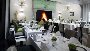 A restaurant with tables set for dining, a fireplace, and decorative lighting. - Hôtel Lensotel (Vendin-le-Vieil)