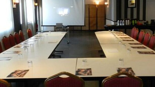 A conference room with a long table, red chairs, a projector screen, and a presentation screen. - Hôtel Lensotel (Vendin-le-Vieil)