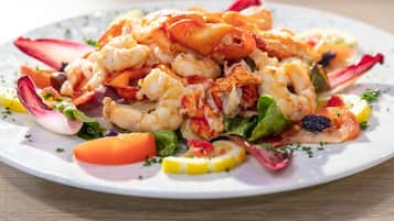 A plate of seafood with shrimp and lobster, garnished with vegetables and herbs.