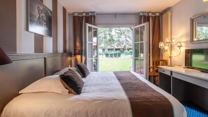 A hotel room with a bed, a desk with a chair, a mirror, and a view of the outdoors. - Hôtel Lensotel (Vendin-le-Vieil)