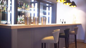 A bar area with a wooden counter, bar stools, and pendant lighting. - Hôtel Lensotel (Vendin-le-Vieil)