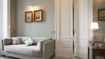 Ein Zimmer mit einem hellen Sofa, einer Tür, einer Lampe und gerahmten Bildern an der Wand.