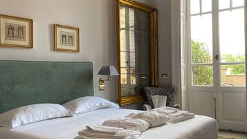 Een opgemaakt bed met witte lakens, een bekleed hoofdbord in het groen en een grote spiegel aan de muur.