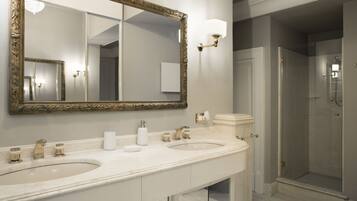 A bathroom with two sinks, a large mirror, and a shower.