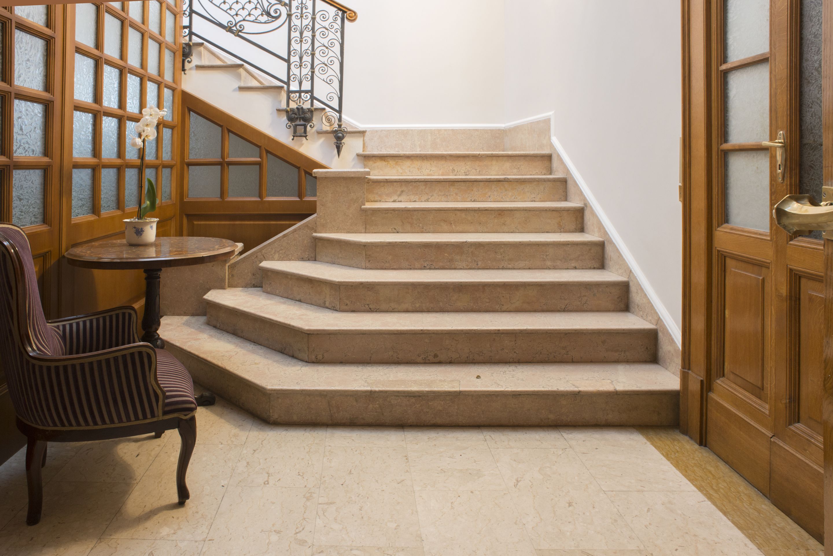Una escalera con barandilla de madera y una silla cerca de una mesa.