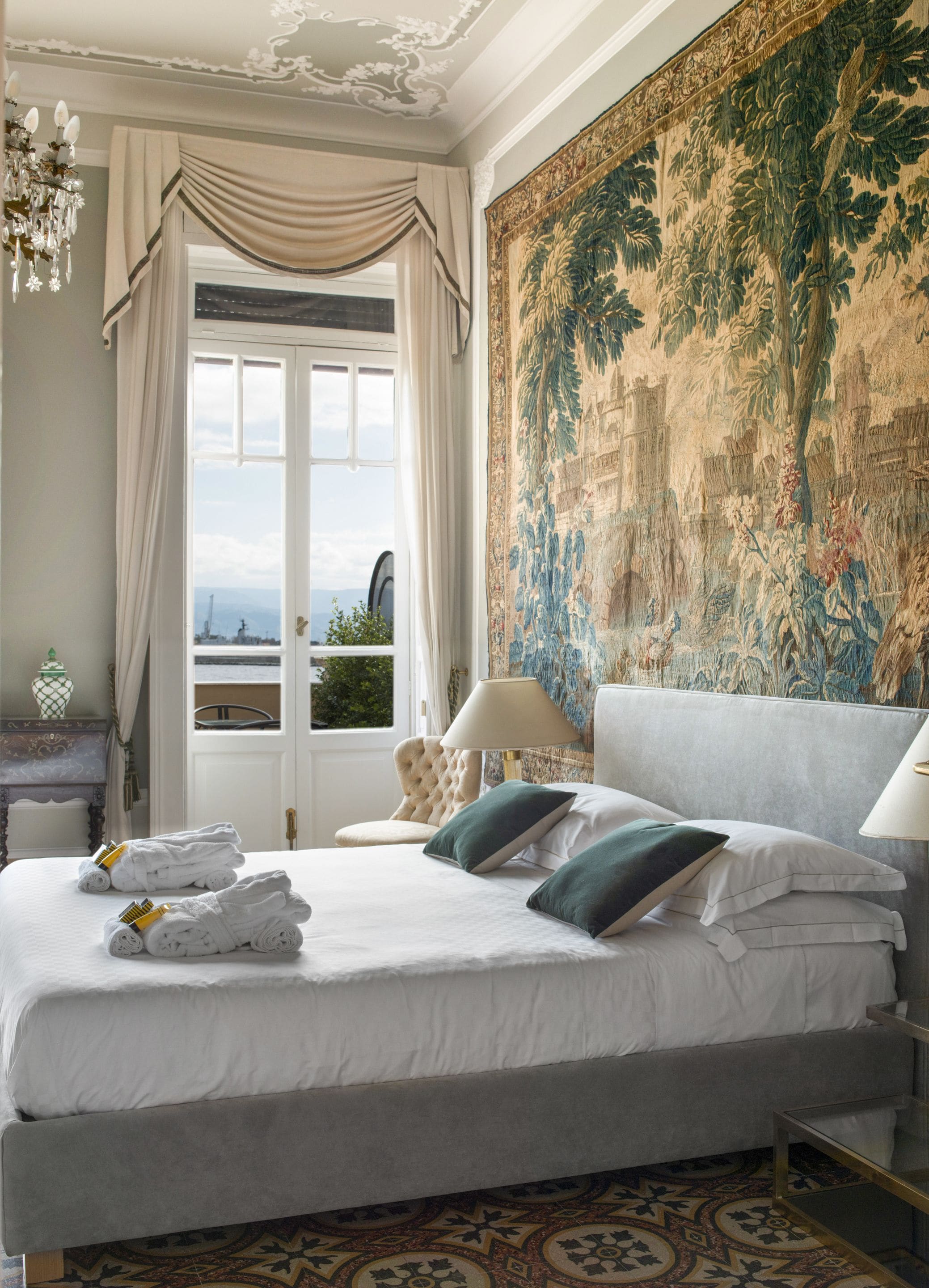 Une chambre d’hôtel avec un grand lit, une vue sur la ville et une tapisserie au mur.