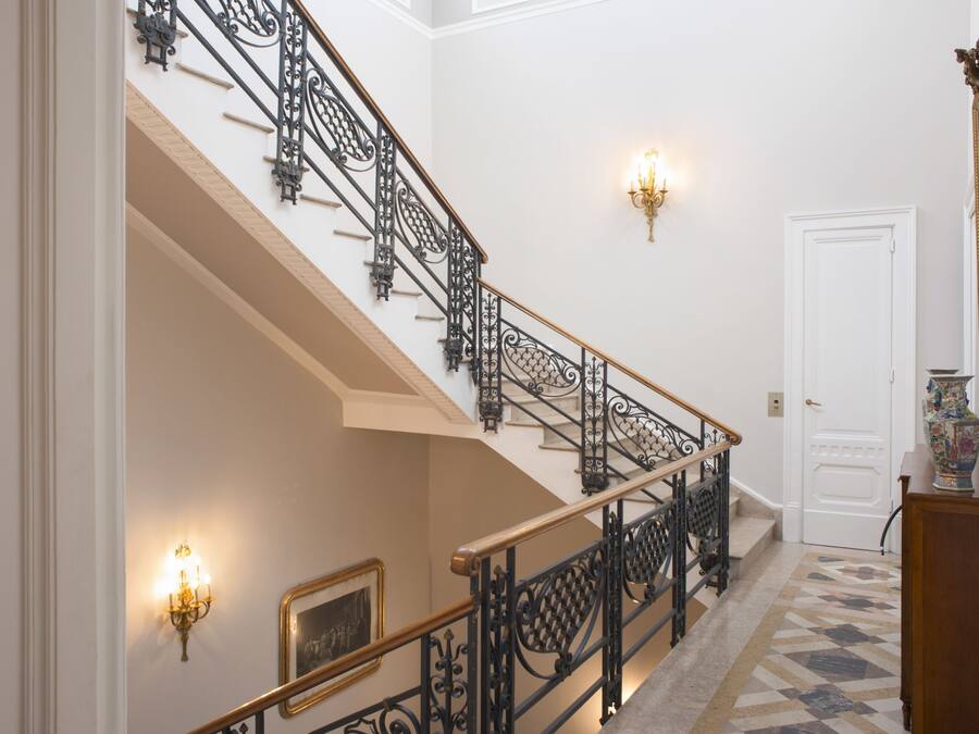 A grand staircase with ornate black railings and a white door at the top.