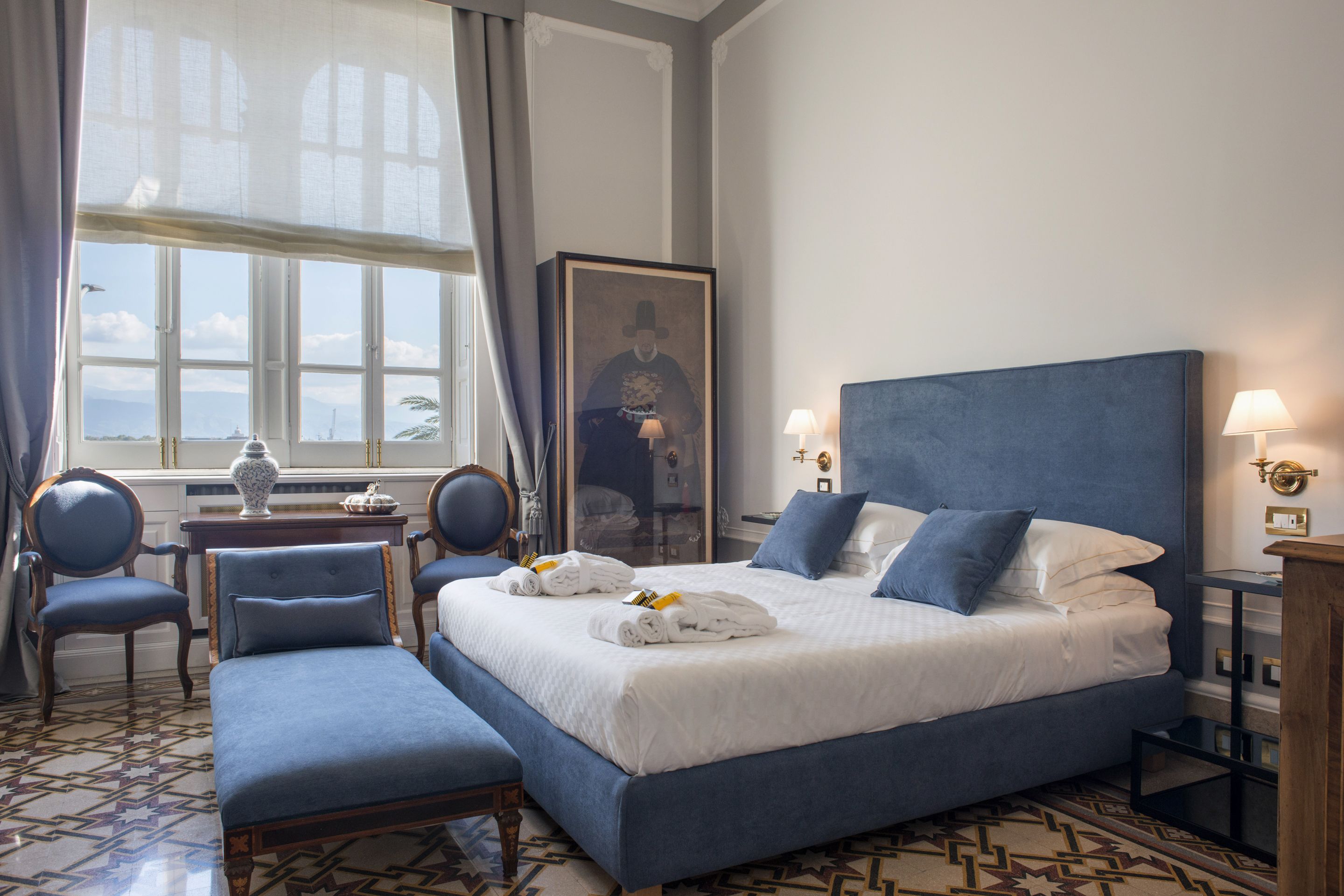 Una camera d'albergo con un letto grande, due poltrone, un tavolino e vista sull'esterno.