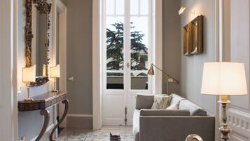 A room with a chandelier, a sofa, a table, and a door leading to a balcony.