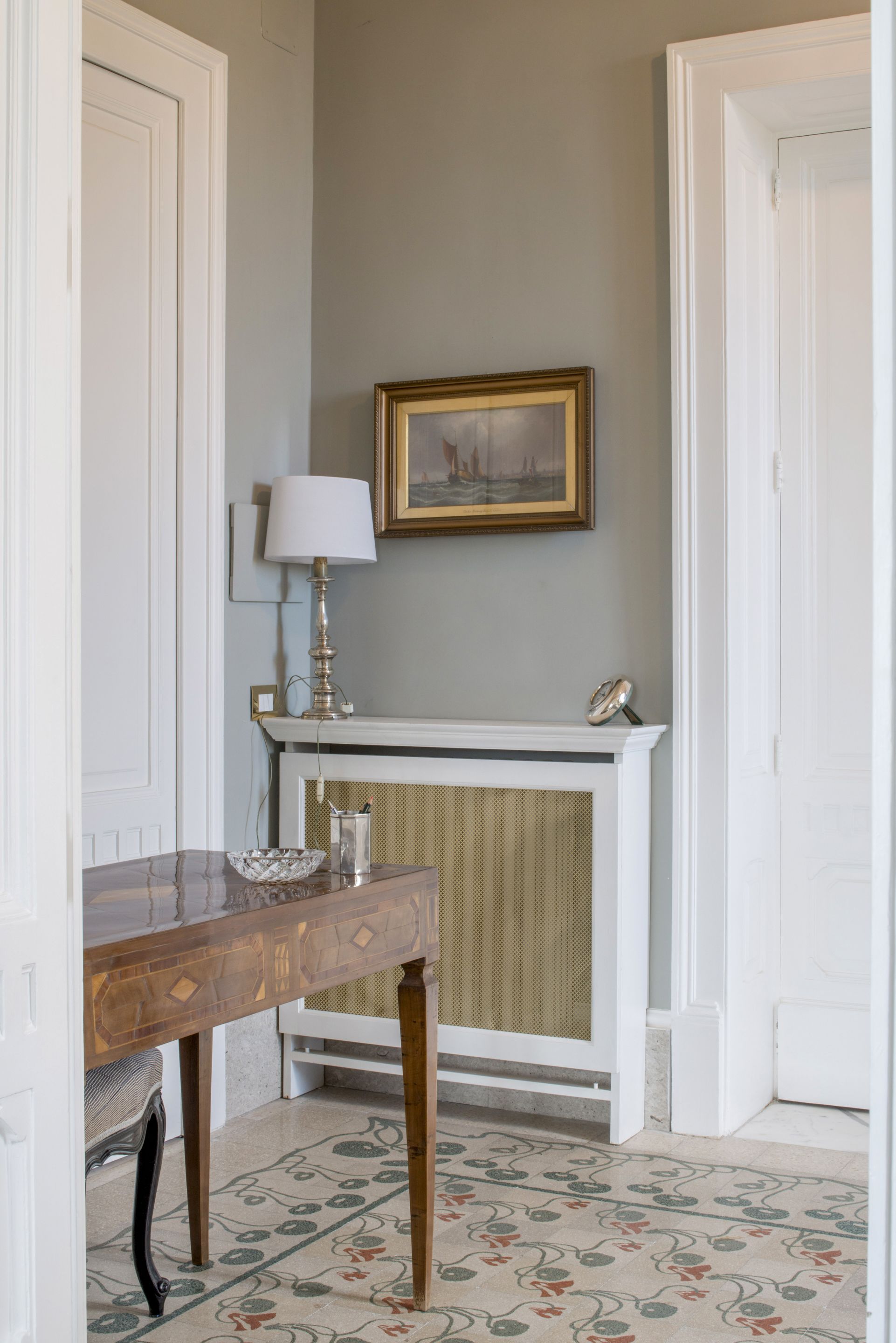 Une pièce avec une table en bois, une lampe, un tableau encadré et une cheminée.