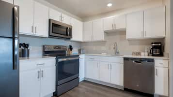 Una cocina moderna con armarios blancos, electrodomésticos de acero inoxidable y piso de madera.