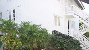 A white building with a white staircase and a garden with various plants. - The Barcelona by Pro Homes Jamaica (Kingston)