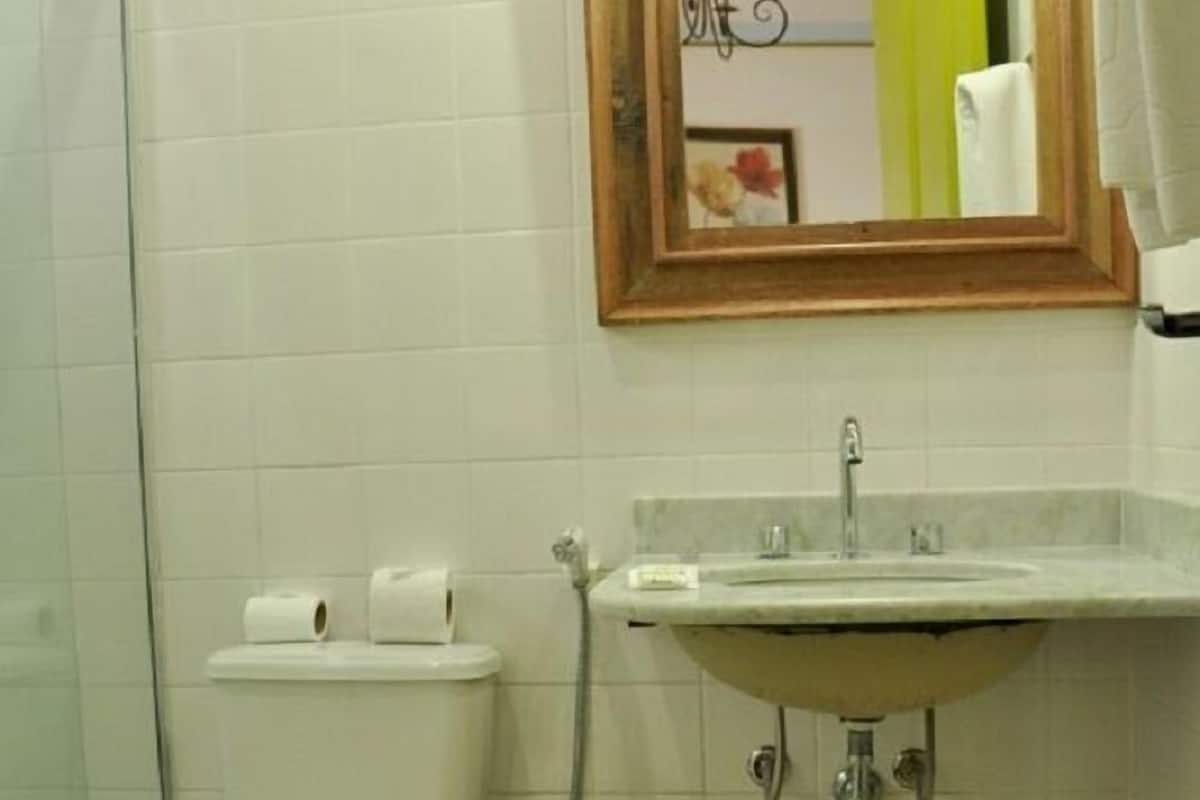 A bathroom with a toilet, sink, and a mirror above the sink.