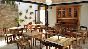 A dining area with wooden tables and chairs, a brick wall, and potted plants.