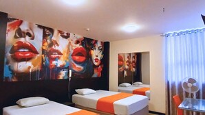 A hotel room with two beds, a dining table, and a fan.