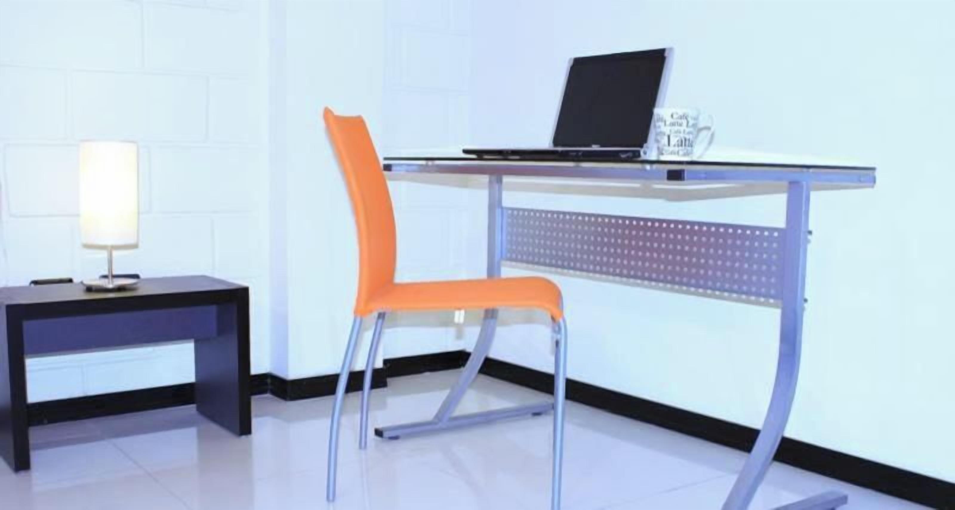 A modern office desk with a laptop, a chair, and a lamp.