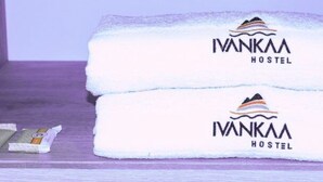 Two folded towels with the 'Iwankaa Hostel' logo on a wooden shelf.