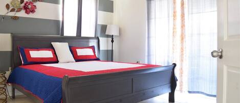 A bedroom with a bed, a nightstand, a lamp, and a window with curtains.