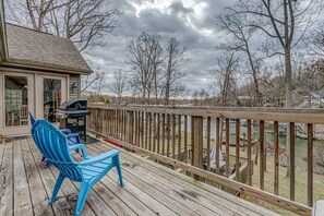A wooden deck with a blue chair and a grill, overlooking a body of water and trees. - Winchester 11A by Pro Homes Jamaica (Kingston)