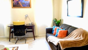 A living room with a sofa, a small table, a chair, and a plant. - Winchester 11A by Pro Homes Jamaica (Kingston)