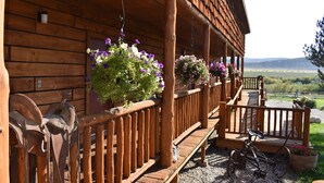 A wooden cabin with a porch, a bicycle, and horse tack. - Beartooth Basin Bunkhouse (Belfry)
