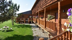 A wooden cabin with a porch, picnic tables, and flower boxes. - Beartooth Basin Bunkhouse (Belfry)