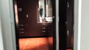 Un pasillo con suelo de baldosas que conduce a una habitación con puerta de madera oscura.