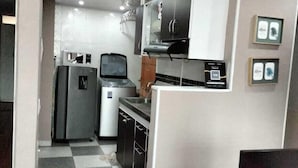 Una cocina pequeña con refrigerador, microondas y lavamanos.