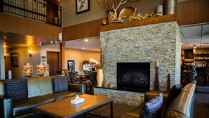 A lobby with a stone fireplace, leather seating, and a bar area.