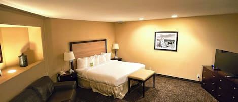 Una habitación de hotel con cama, escritorio, silla, sofá y televisor.