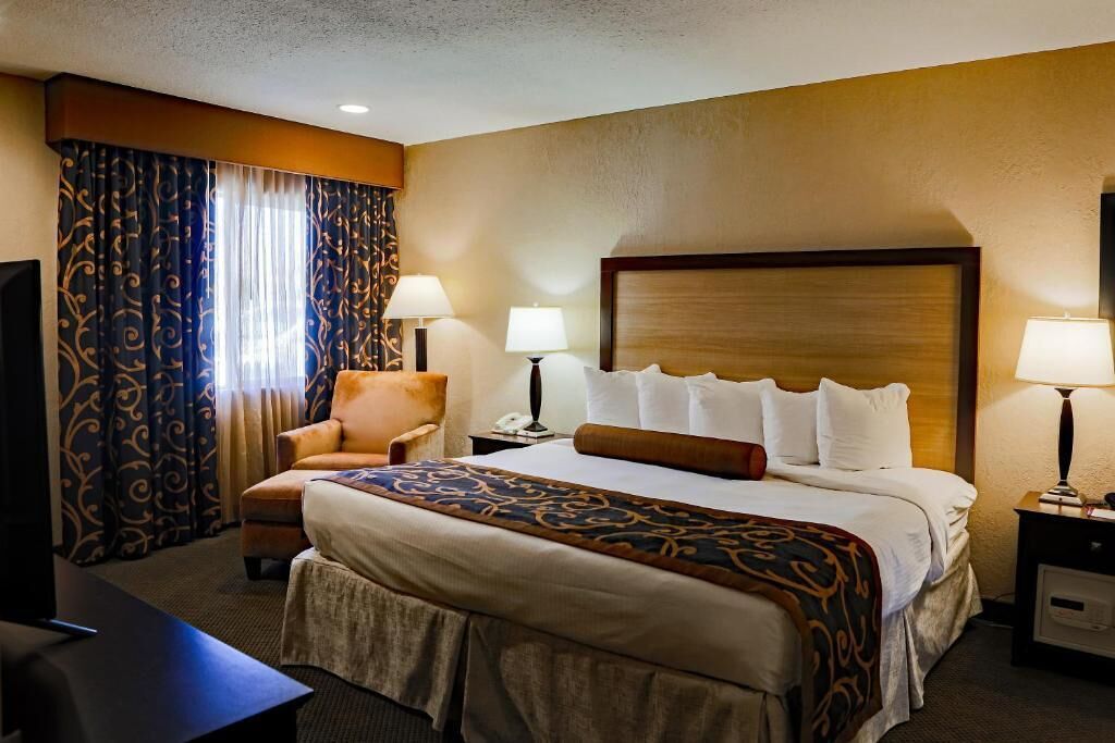 A hotel room with a large bed, two bedside lamps, a chair, a desk, and a television.