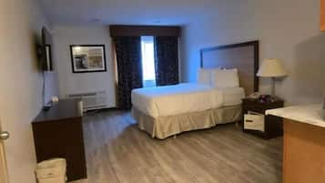 Una habitación de hotel con una cama, un escritorio, un televisor y una mesita de noche.