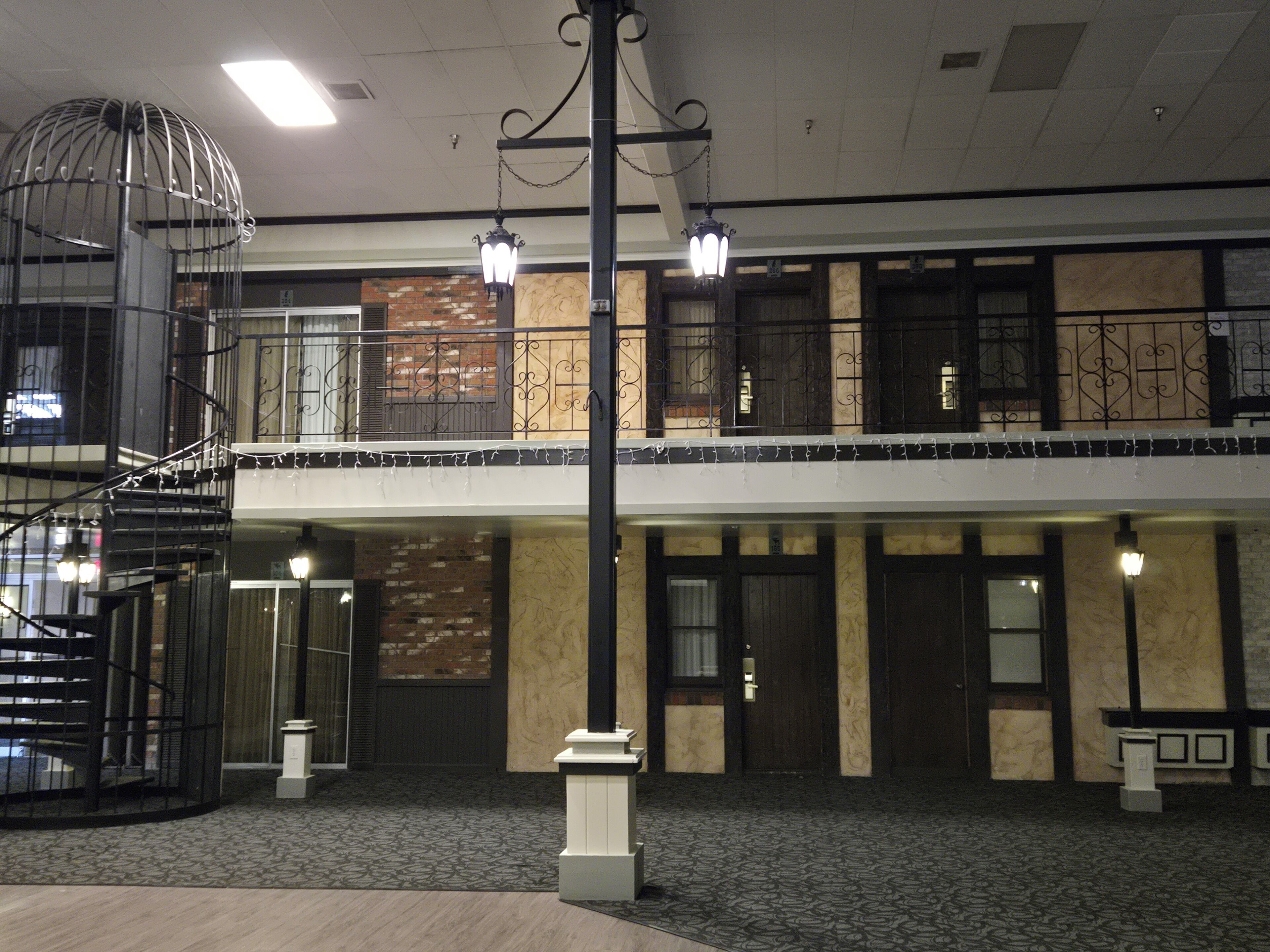 Hall d'ingresso di un hotel su più livelli, con una scala a chiocciola, un lampadario e un tappeto decorato.