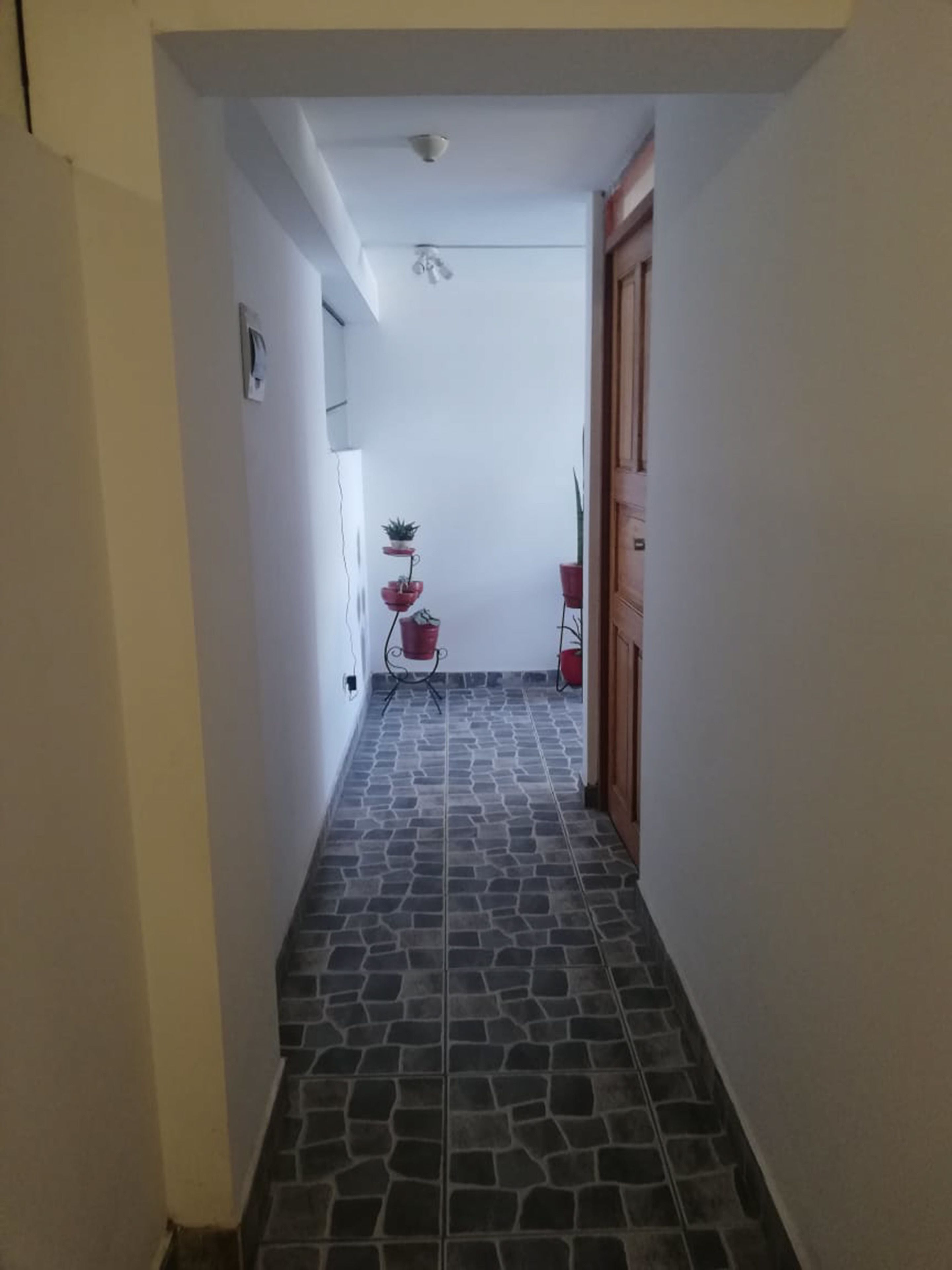 A narrow hallway with a tiled floor, a ceiling fan, and a door at the end.