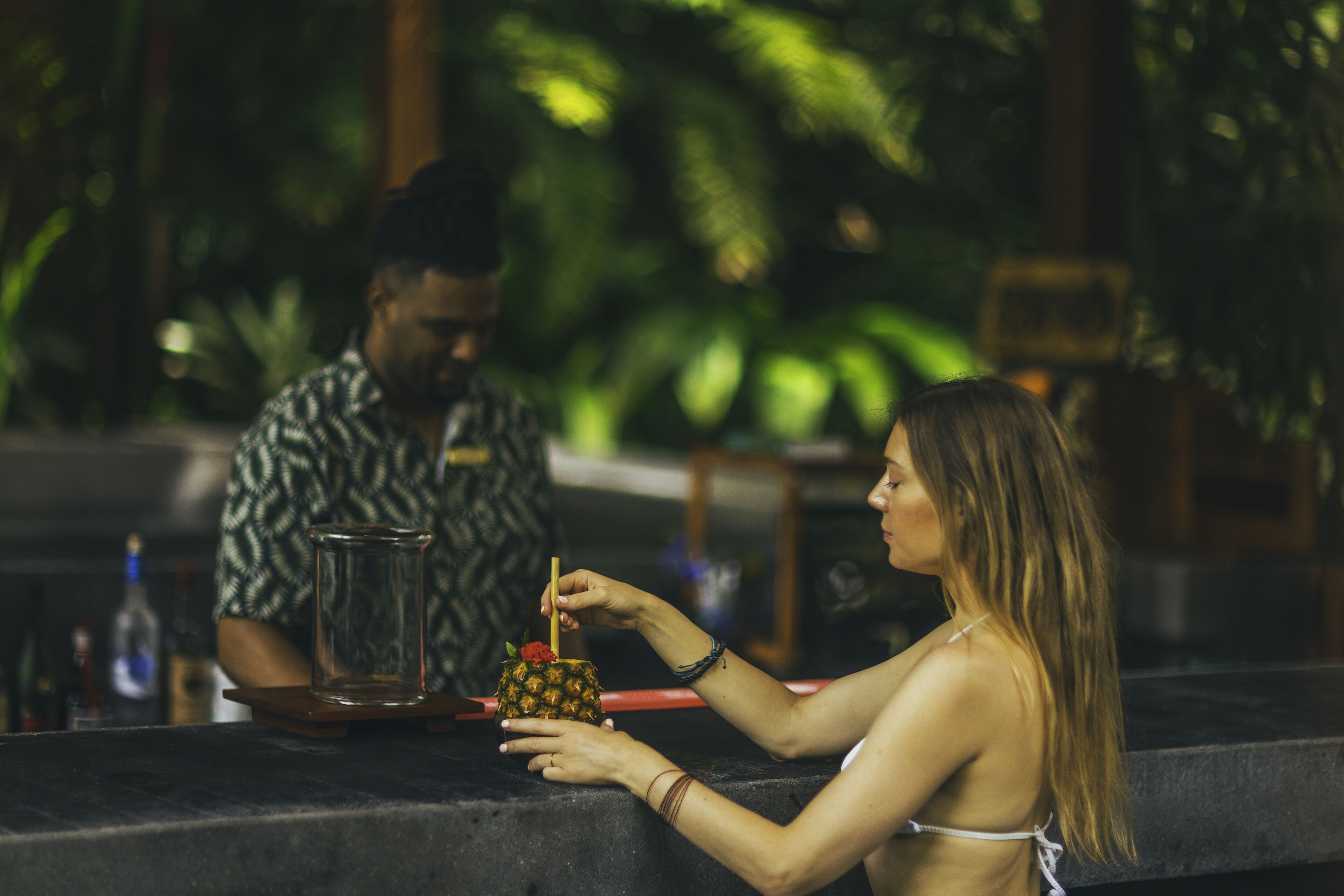 A person preparing a drink with a pineapple on the counter.
