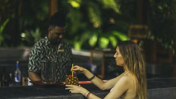A person preparing a drink with a pineapple on the counter.
